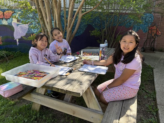 Three students sit at a table for art