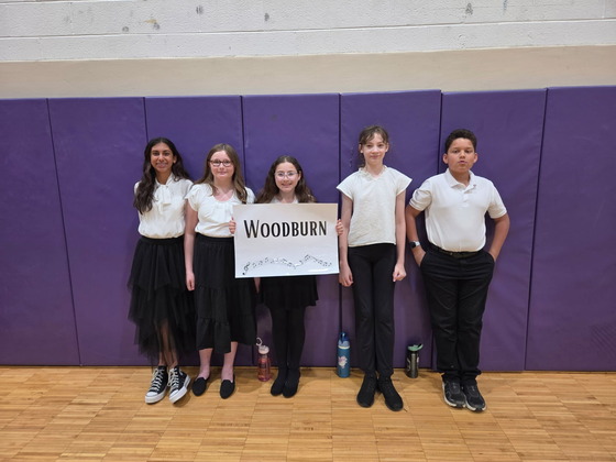 5 students pose with a sign that says "Woodburn" 