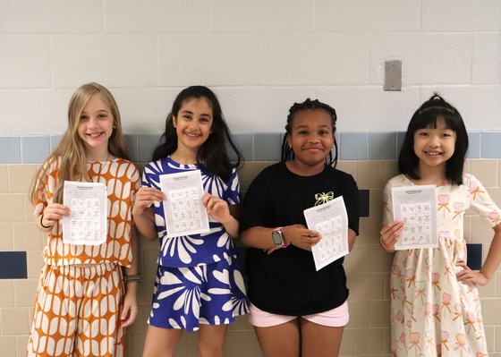 Picture of 4 students presenting their Bee Kind Spirit Week Bingo Charts
