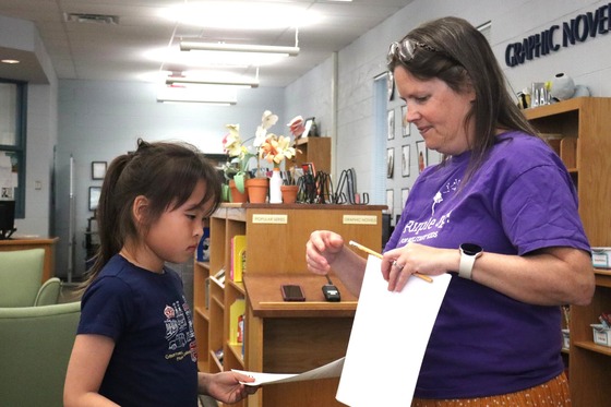 Picture of a student receiving a CARES Pizza award for responsibility by Principal Riley