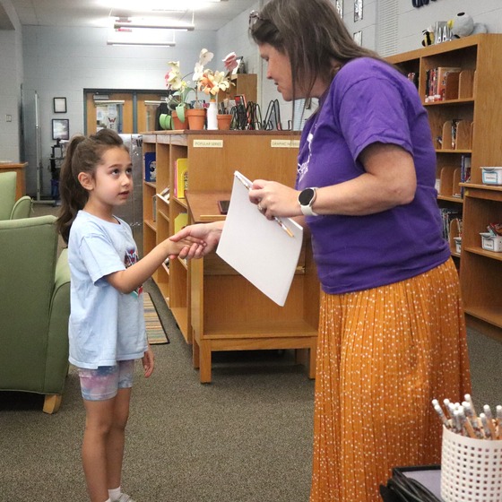 Picture of a student receiving a CARES Pizza award for responsibility by Principal Riley