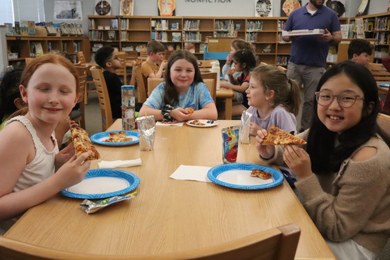 A picture of a table of students eating pizza after receiving their CARES Pizza award for responsibility