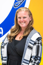 Mrs. Ehrman in front of fairview blue and yellow logo