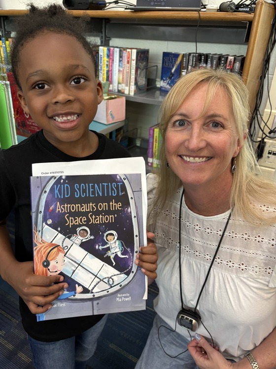 Author Sue Fliess with a kindergarten student who is holding one of her books.