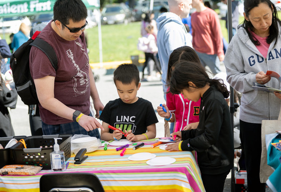Kids color at an outdoor table while parents look on