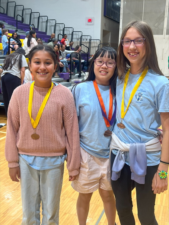 Three girls standing with medals around their necks