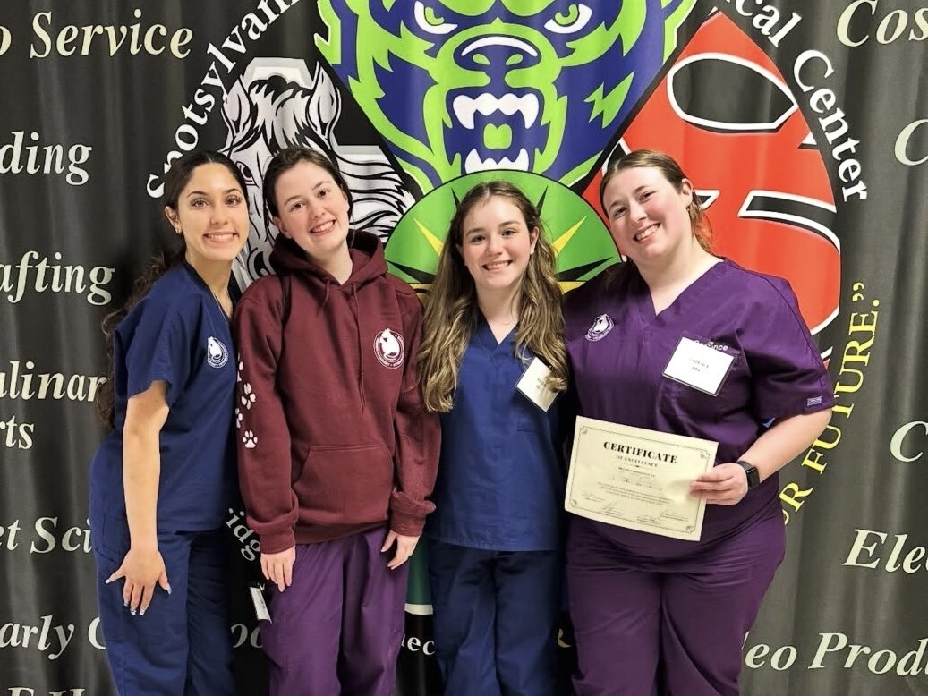 photo of four female students in scrubs, one with a certificate