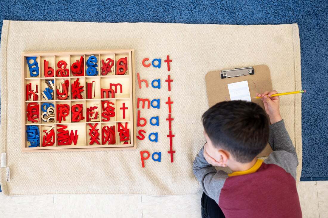 A Montessori student working with the moveable alphabet