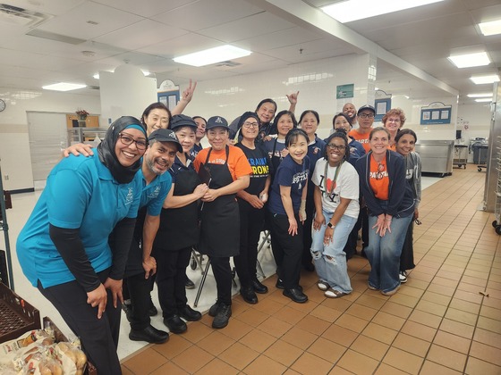 People in a cafeteria smiling and giving a thumbs up