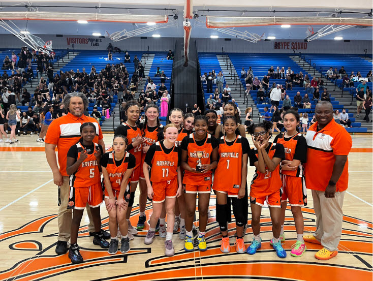 group of students in orange jersey with coaches