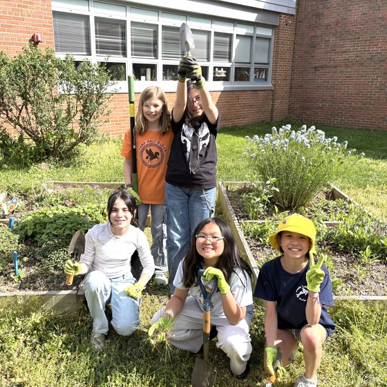 A picture of a group of students posing in front of their garden