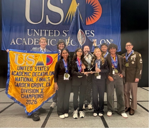 Members of the TJ Academic Decathlon Team standing on stage with trophy right after winning National Championship.