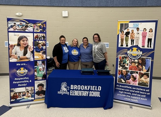 Four adults standing behind a Brookfield table 
