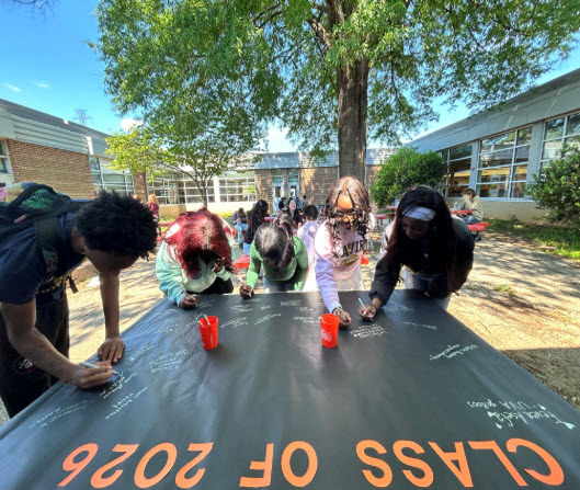photo of students signing a black decision day 2026 poster