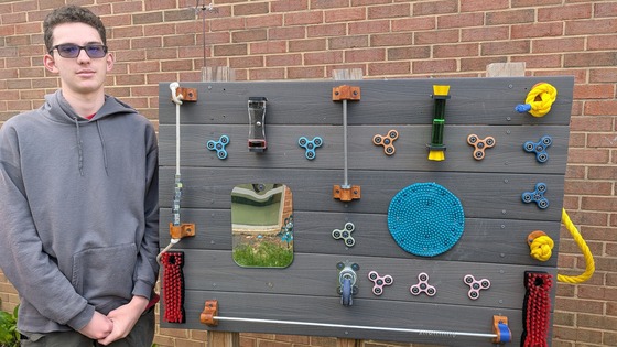 Student standing next to new sensory board