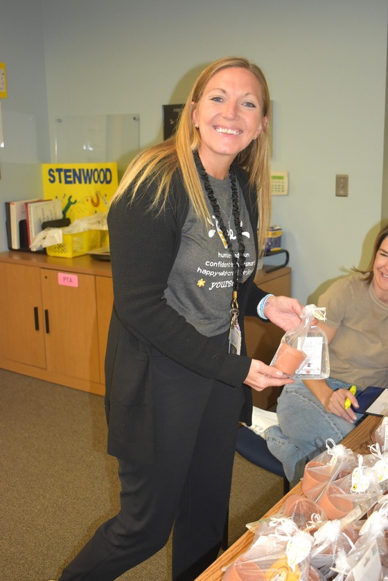 A picture of Mrs. Curry receiving her gift card and desk plant