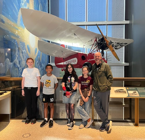 A picture of 4 students and one parent chaperone at the Air and Space Museum