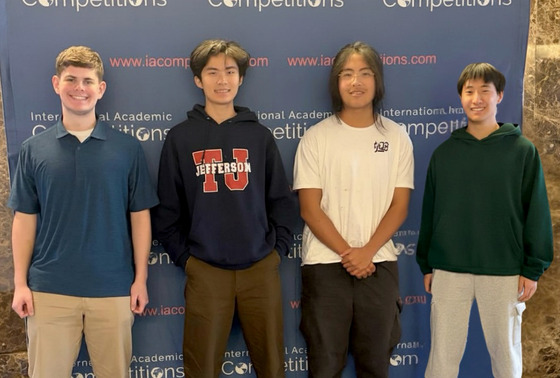 TJ's History Bowl Team stands in front of a IAC banner.