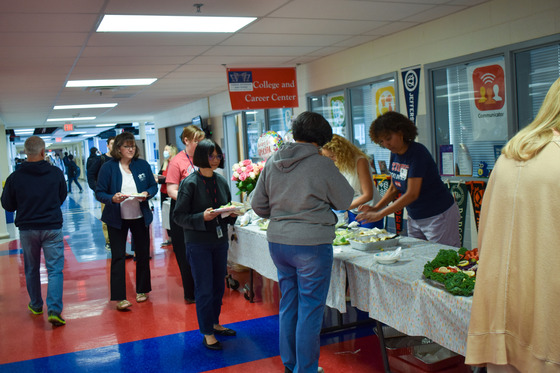 TJ Staff standing in line beside a table as PTSA members serve them lunch.