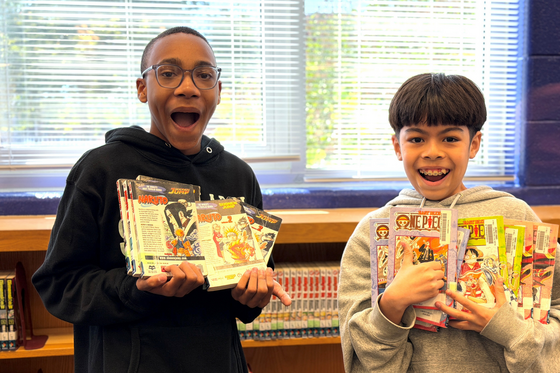 Two students holding library books with excited faces