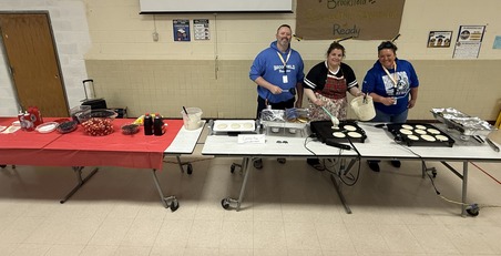 Three administrators serving pancake breakfast