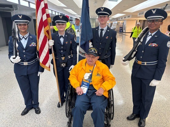 Air Force JROTC students in uniform standing behind World War II veteran seated in wheelchair