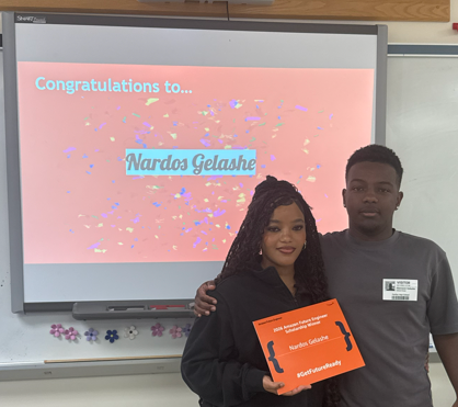 Student standing beside parent holding scholarship certificate