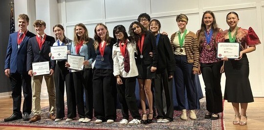 Students standing together with medals around their necks and holding certificates