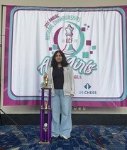 Student standing beside chess trophy