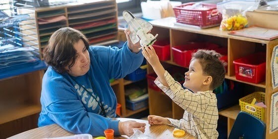 Teacher and preschooler seating while playing together