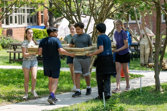 students carrying a raised bed to build a garden at their school