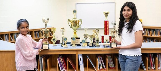students next to many of their spelling bee trophies