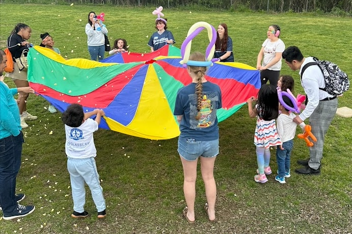 Students and families playing with a parachute.