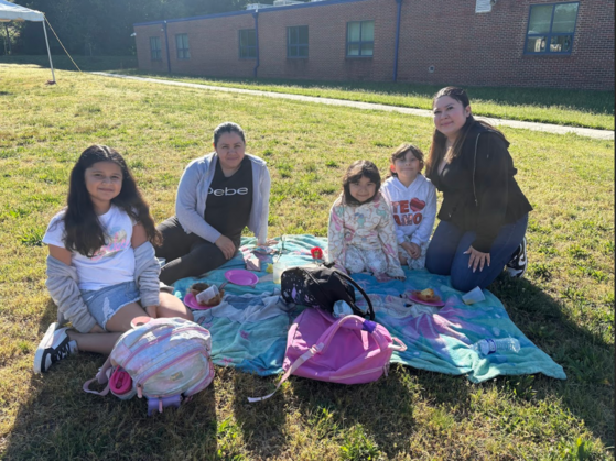 Students with their moms on the grass. 