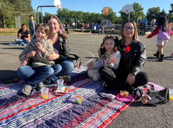 Students sitting with their moms on the playground.
