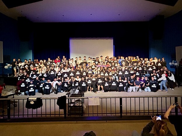 Students on a stage holding up t-shirts