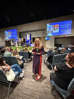 female with music award in FCPS auditorium surrounded by people