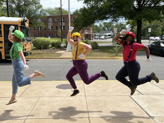 Administrators jumping in the air while dressed as Mario Kart video game characters