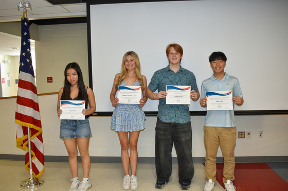 TJ's Memorial Scholarship Winners standing in front of a screen.