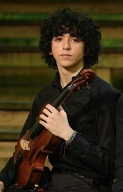 A male student wearing a black dress shirt poses with a small strings instrument