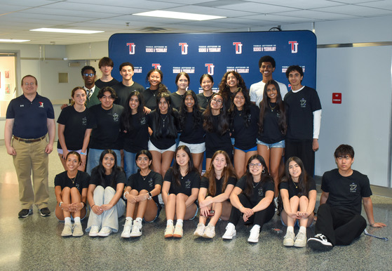 The majority of the tjSTAR committee stands in front of a TJ backdrop.