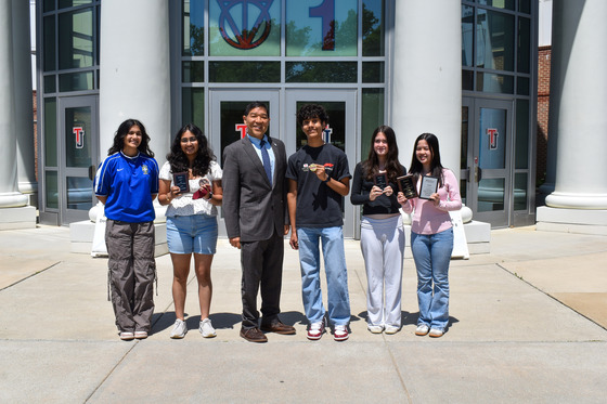 Five members of TJ's Speech Team that won awards this season posing in front of the main entrance of TJ with Principal Mike Mukai