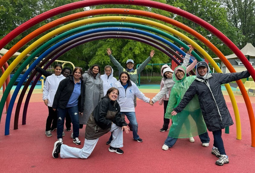 group of teachers under rainbow colored playground equipment