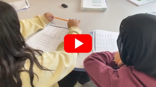 students doing work at a desk to convey secondary literacy work