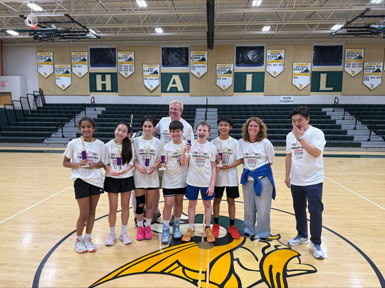 Forestville Elementary 6th grade players and coaches stand on a gym court at Langley High School holding trophies.