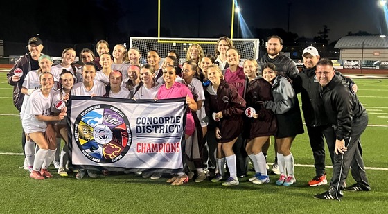 image of girls soccer team after winning the district championship with the district banner in front of them