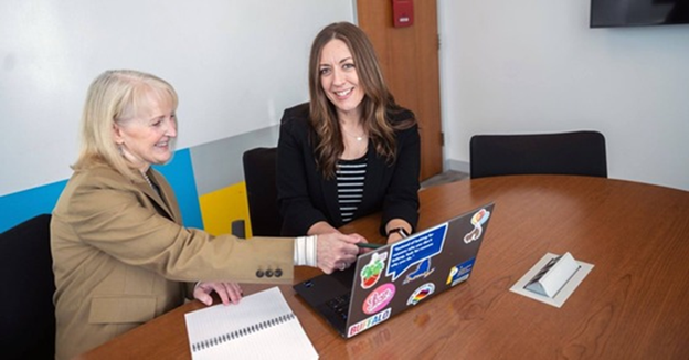 Teachers sitting and pointing at a computer 