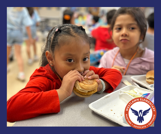 a student eats a chicken sandwich in the school cafeteria