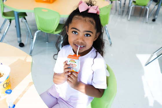 photo of girl with bow in hair drinking from a juice box