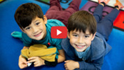 two students laying on the floor smiling at the camera